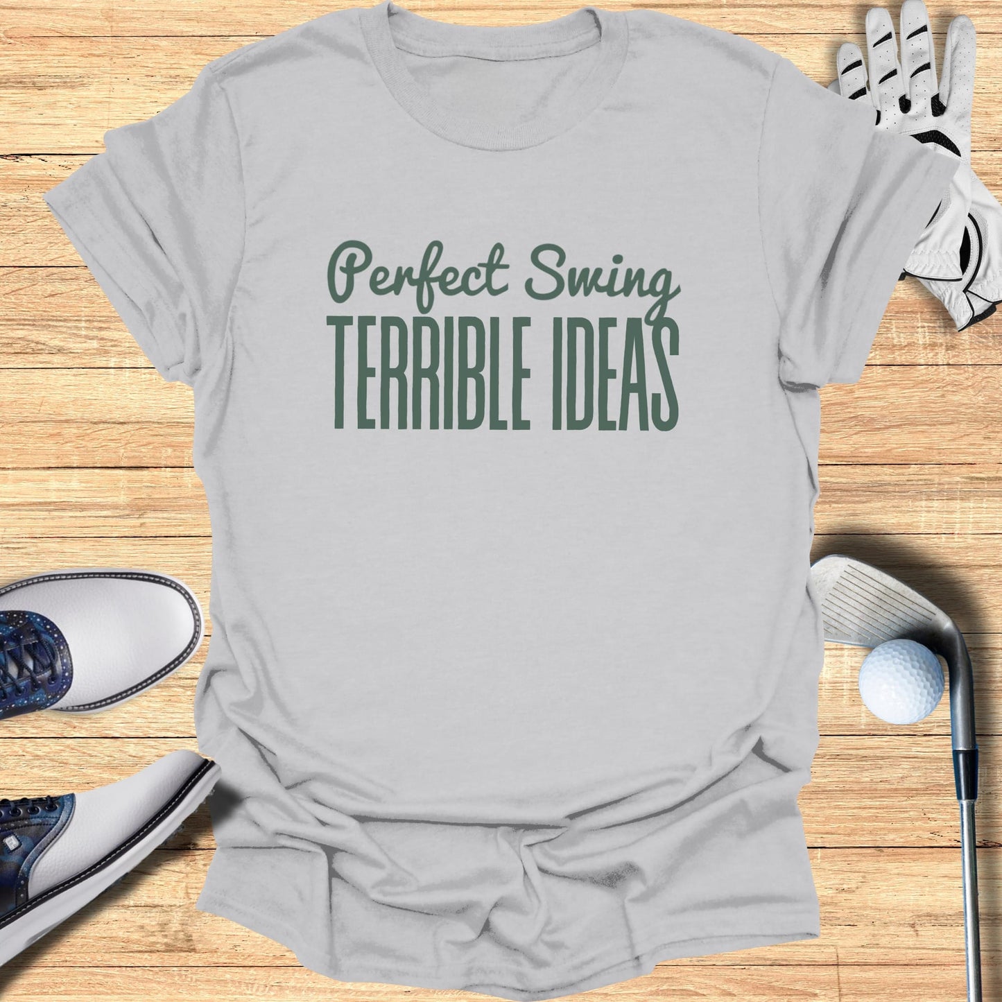 Grey t-shirt with "Perfect Swing TERRIBLE IDEAS" text, golf accessories.