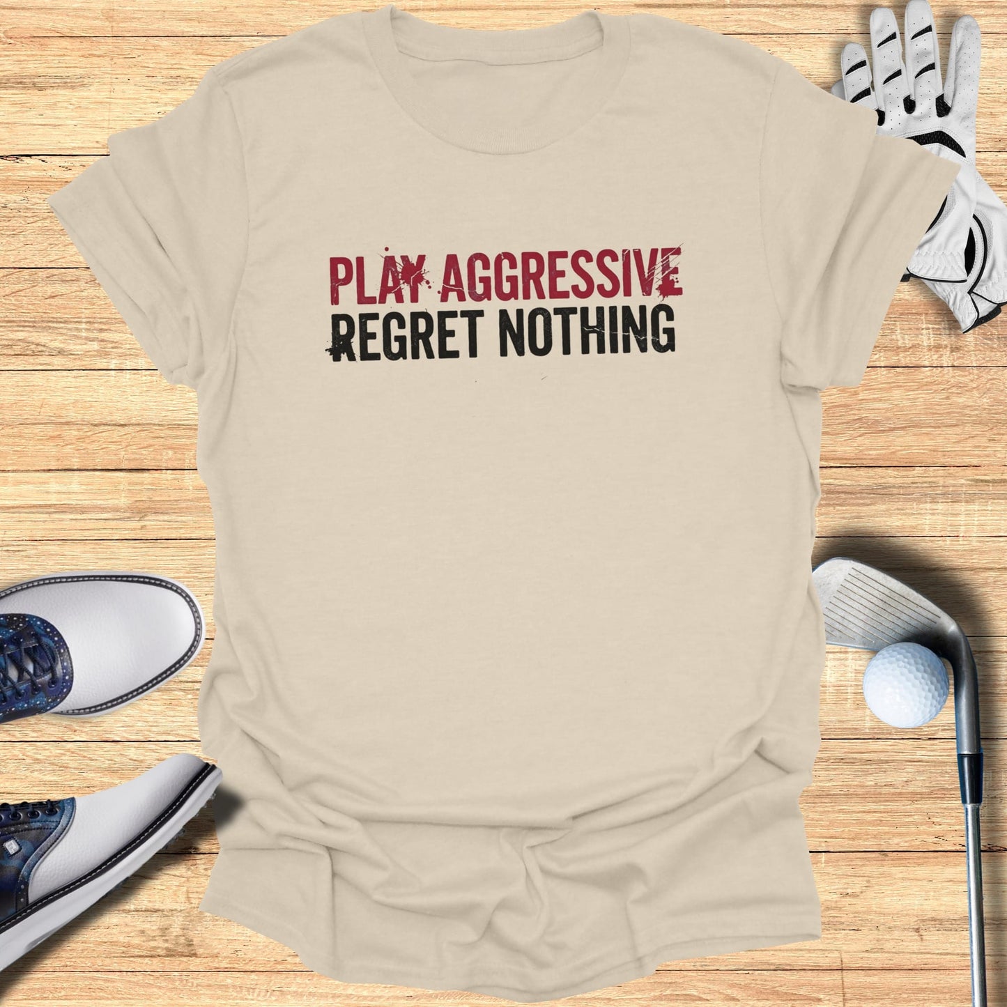 Tan t-shirt with "PLAY AGGRESSIVE REGRET NOTHING" text and golf accessories.