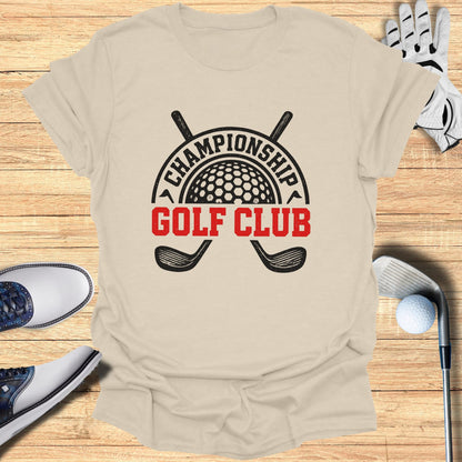 Championship Golf Club logo on a tan t-shirt with golf accessories.