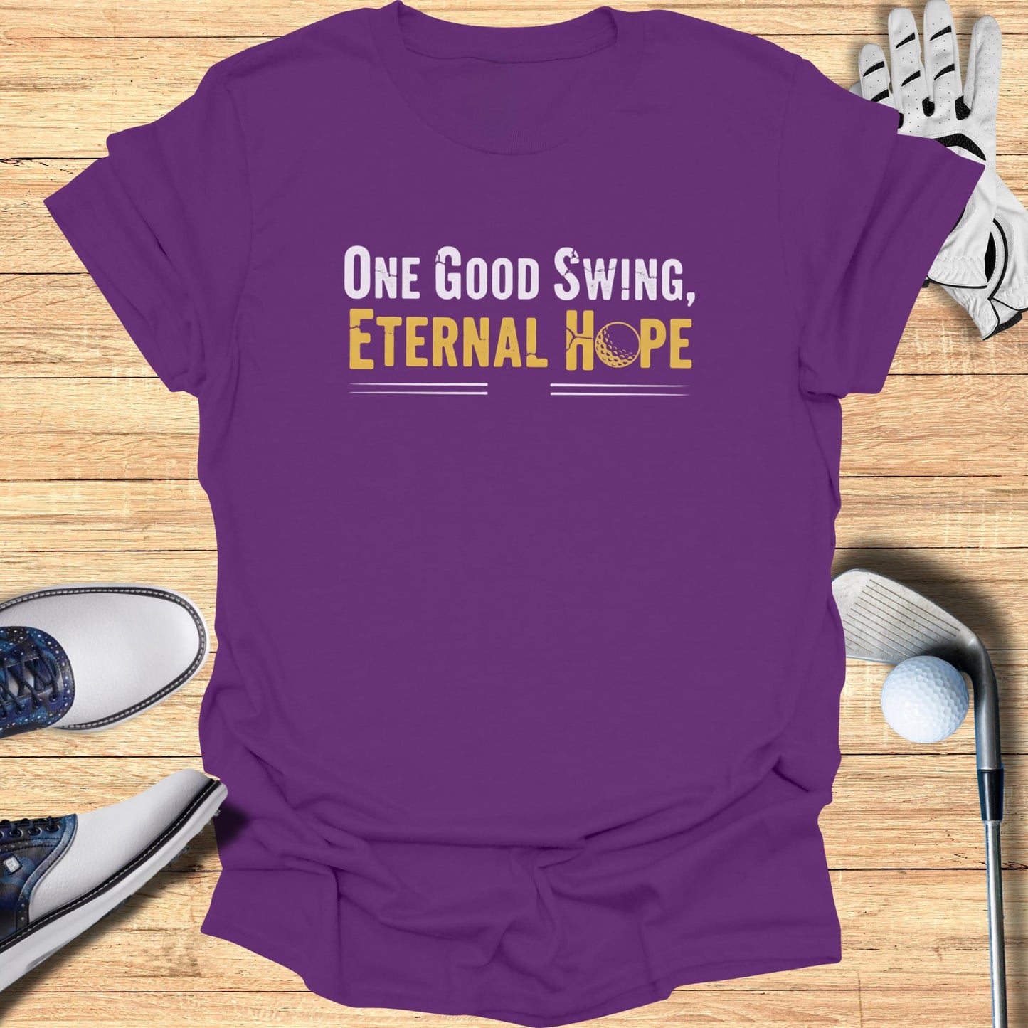 Purple t-shirt with "One Good Swing, Eternal Hope" text and golf accessories.