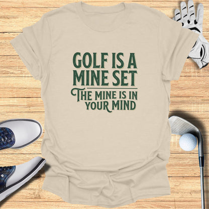T-shirt with "Golf is a mindset" text, surrounded by golf accessories.