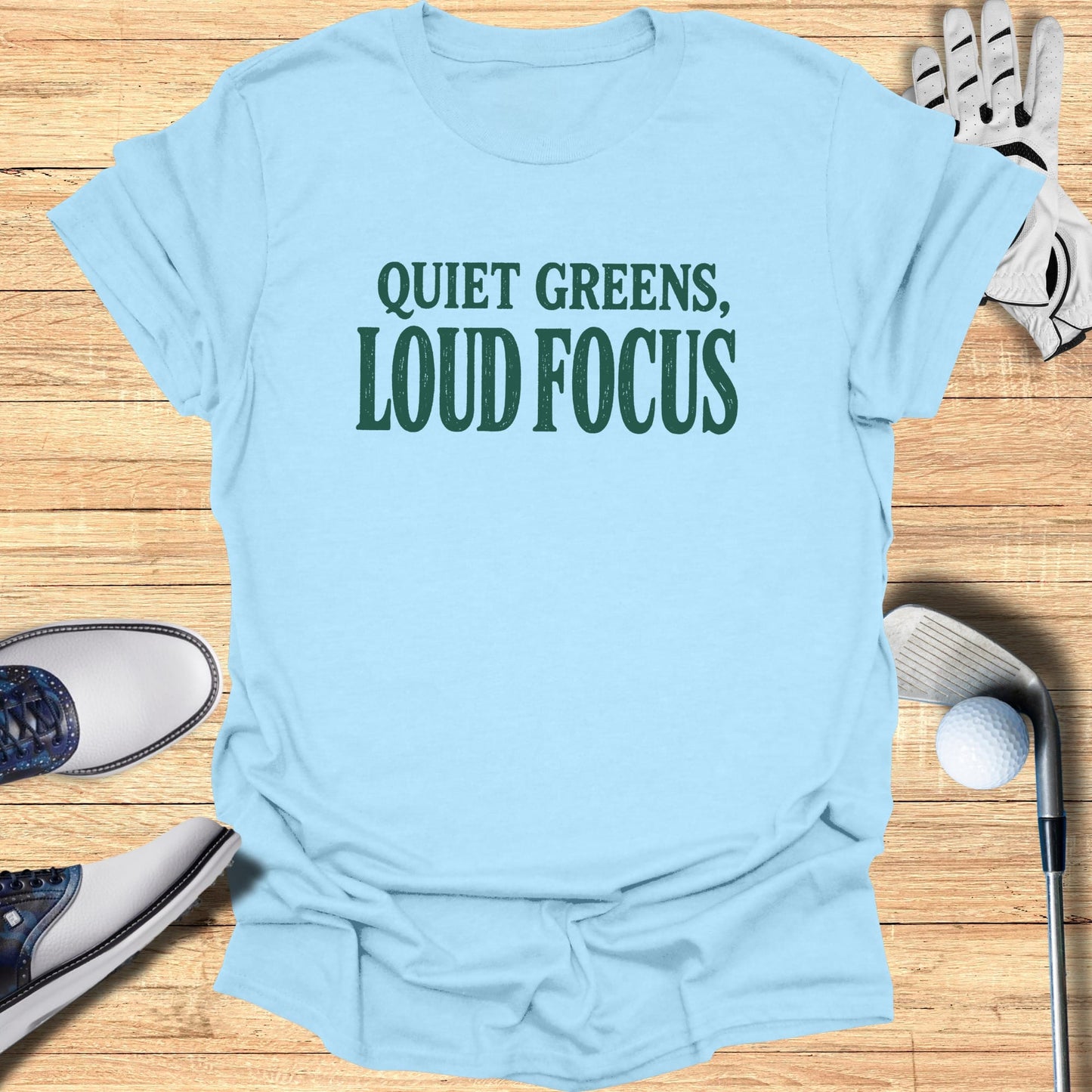 Light blue t-shirt with "QUIET GREENS, LOUD FOCUS" text.