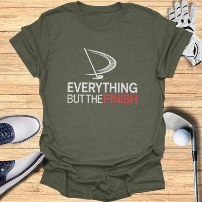 Olive green t-shirt with "EVERYTHING BUT THE FINISH" text and golf accessories.