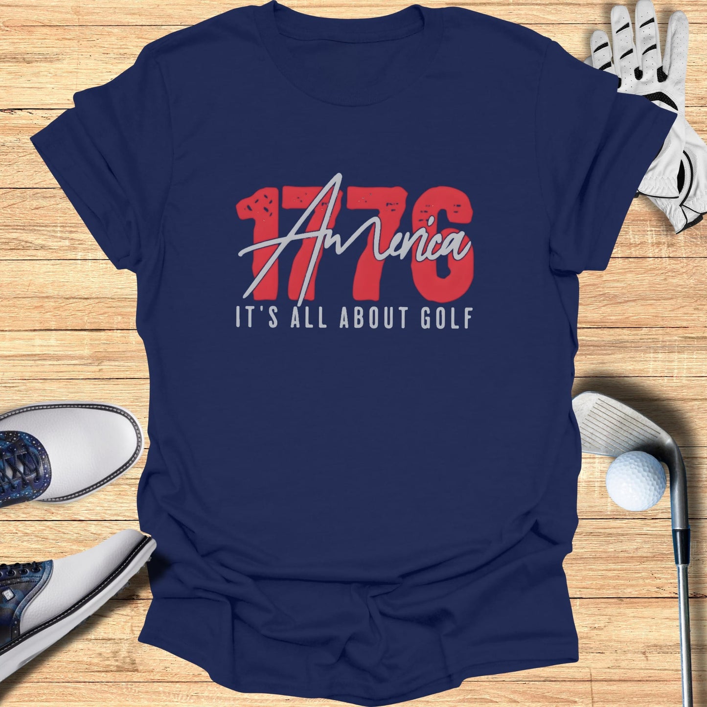 Navy t-shirt with "1776 It's All About Golf" graphic, golf shoes, and ball.