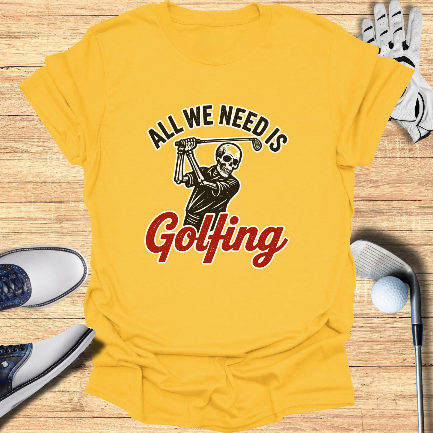 Yellow t-shirt with graphic of skeleton golfing, text "ALL WE NEED IS Golfing".