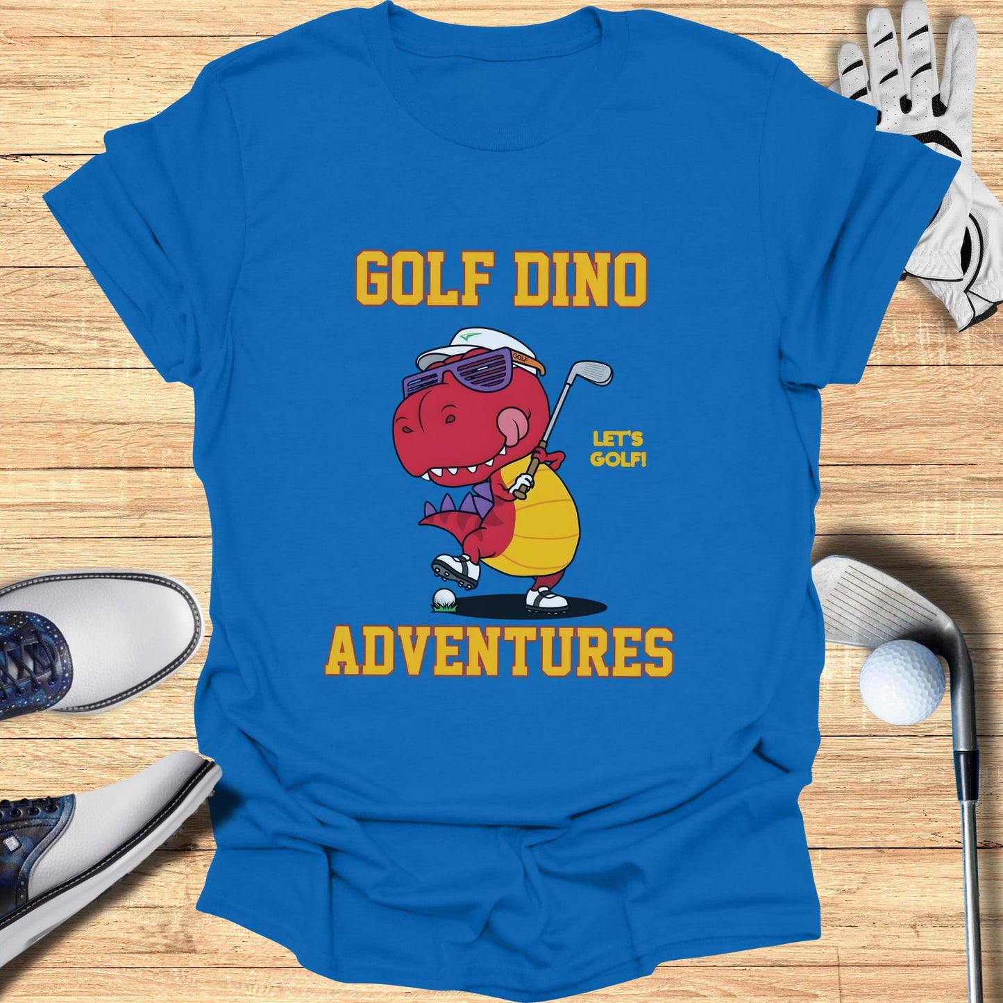 Blue t-shirt with cartoon dinosaur playing golf and text "GOLF DINO ADVENTURES".