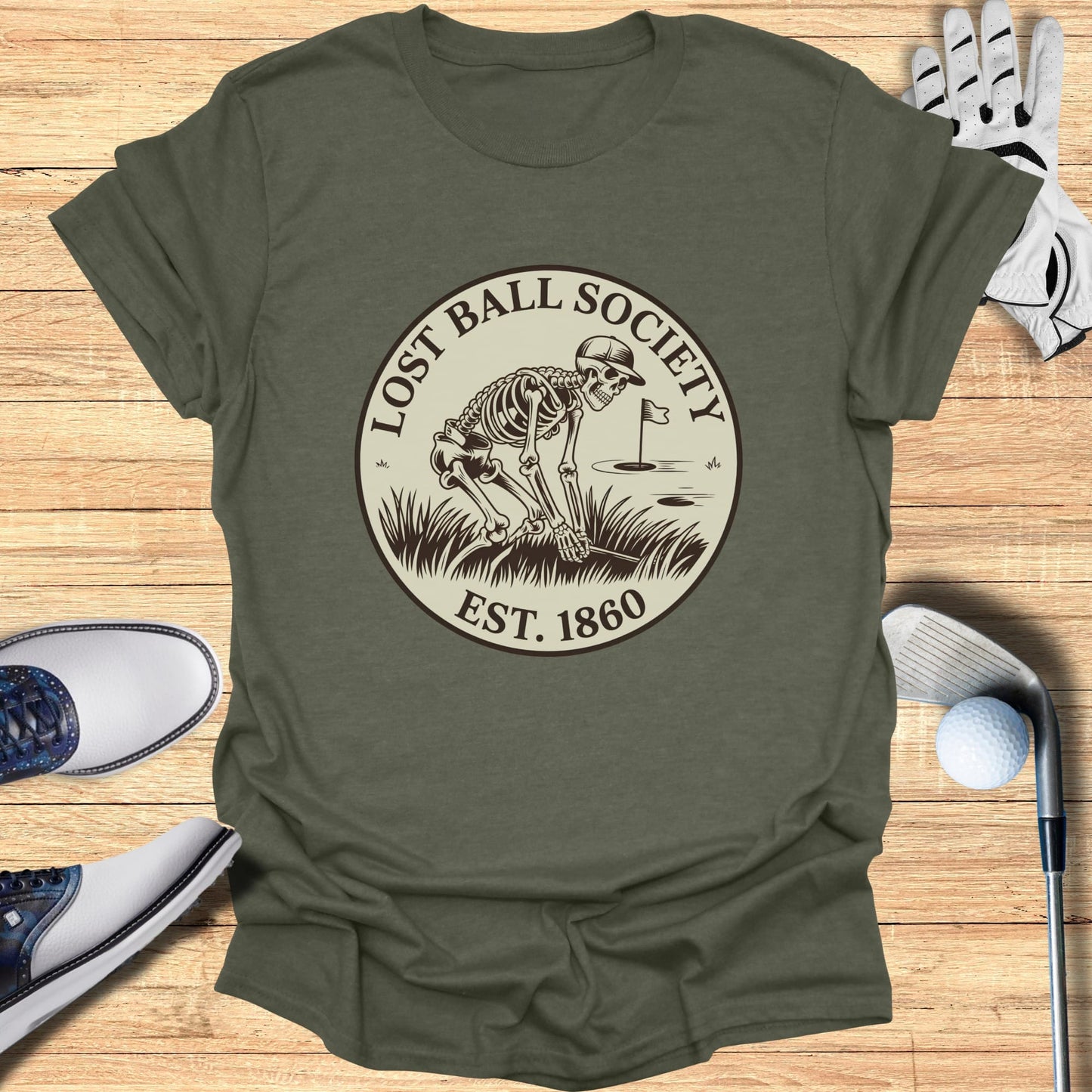 "Lost Ball Society" logo with skeleton golfing on olive green t-shirt.