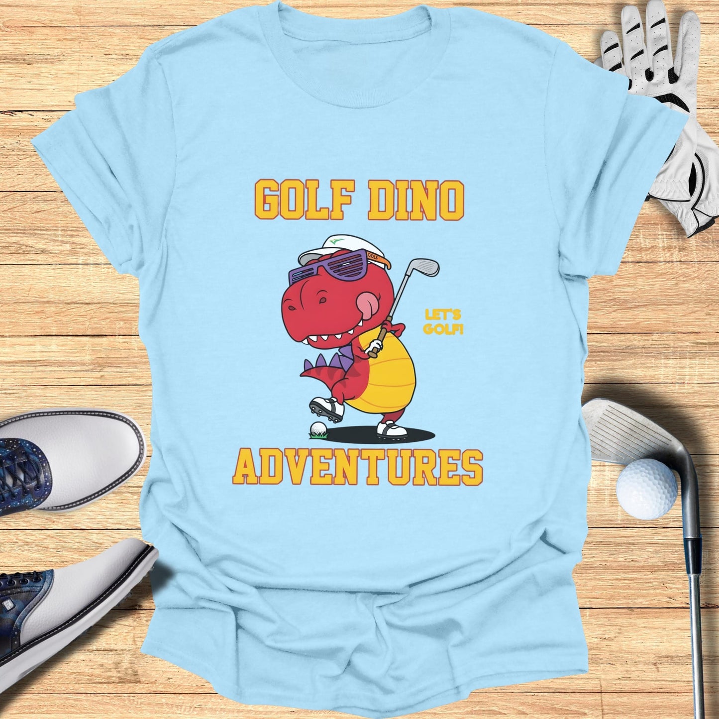 Light blue t-shirt with a cartoon dinosaur wearing sunglasses and playing golf.