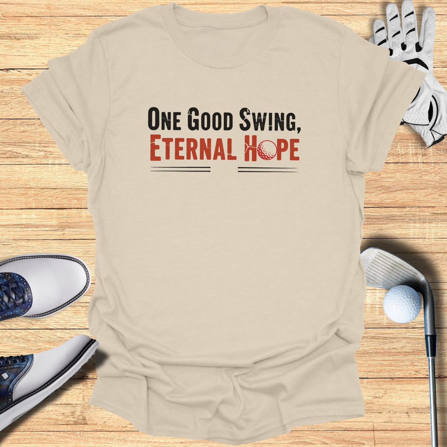 Beige t-shirt with "One Good Swing, Eternal Hope" text and golf items.