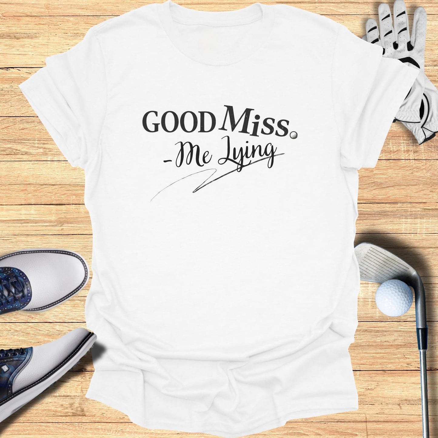 White t-shirt with "Good Miss - Me Lying" text and golf accessories.