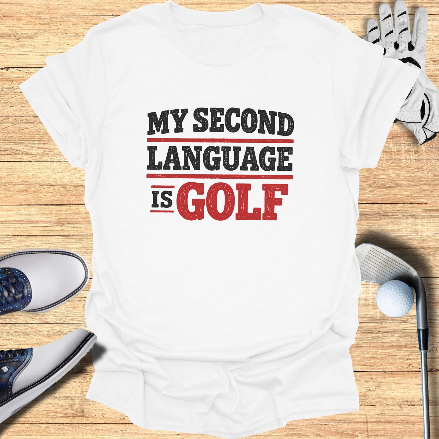 White t-shirt with text "MY SECOND LANGUAGE IS GOLF" and golf accessories.