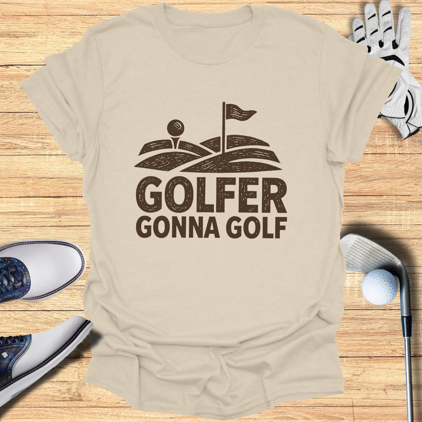 GOLFER GONNA GOLF text design on a tan t-shirt with golf equipment.
