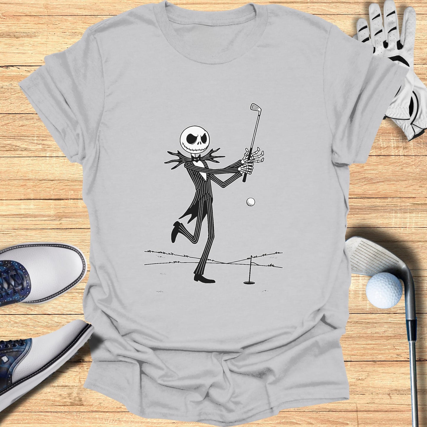 Jack Skellington swings a golf club on a t-shirt with golf accessories.