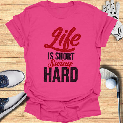 Pink t-shirt with "Life is Short Swing Hard" text, golf clubs, and shoes.