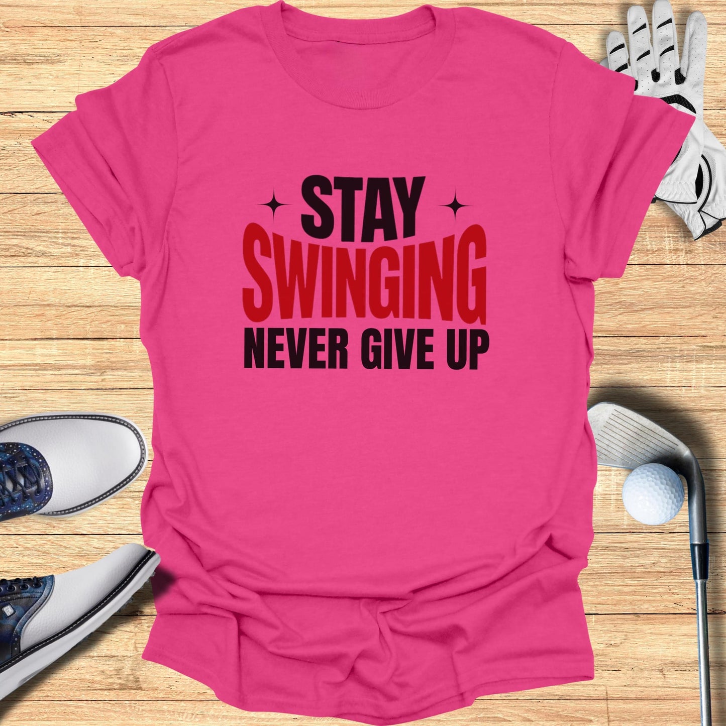 Pink t-shirt with "Stay Swinging Never Give Up" text, golf clubs, shoes, and ball.