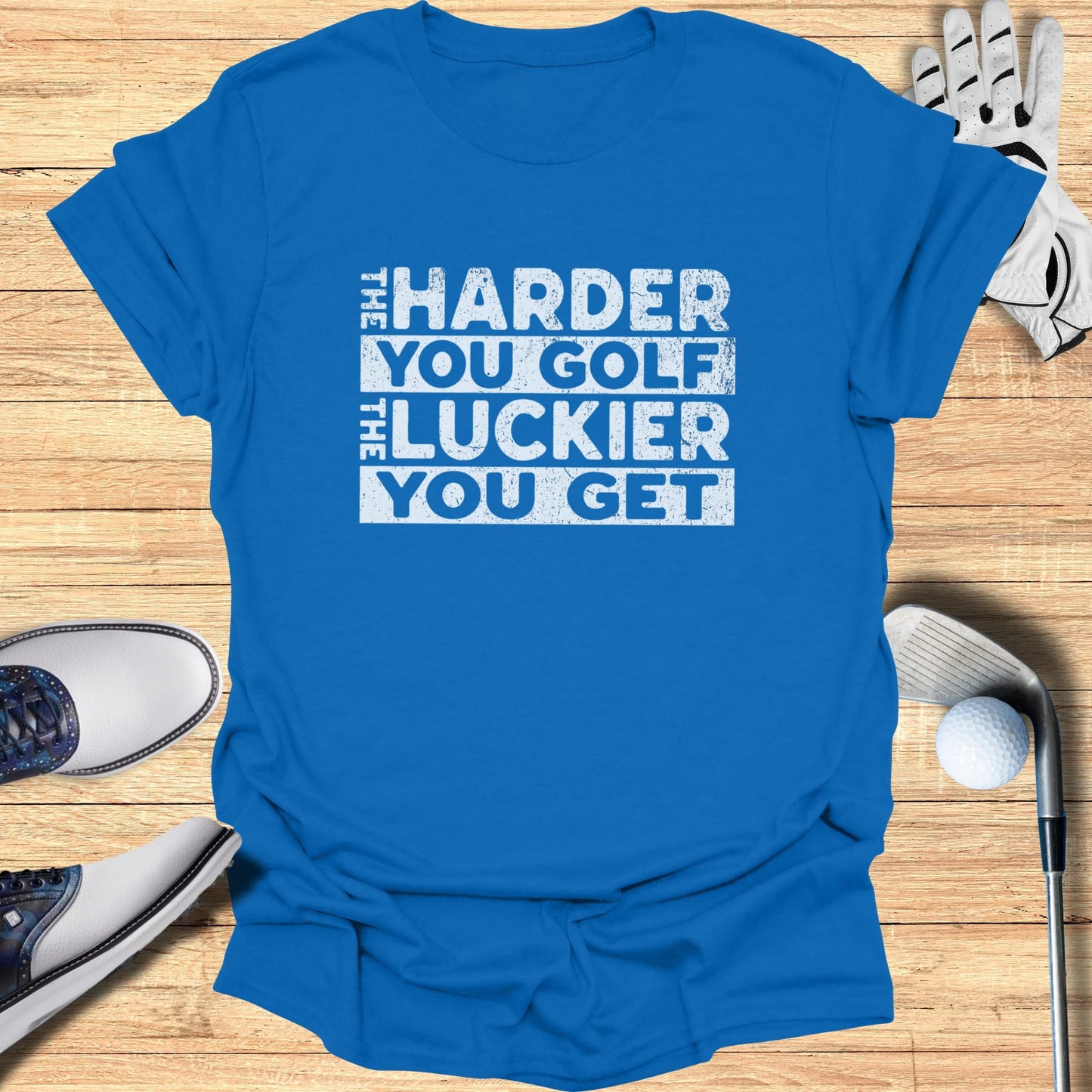 Blue t-shirt with white text "The Harder You Golf The Luckier You Get".
