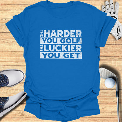 Blue t-shirt with white text "The Harder You Golf The Luckier You Get".