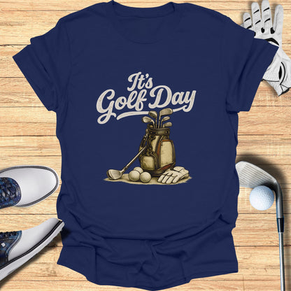 Navy t-shirt with "It's Golf Day" text, golf bag, clubs, and balls.