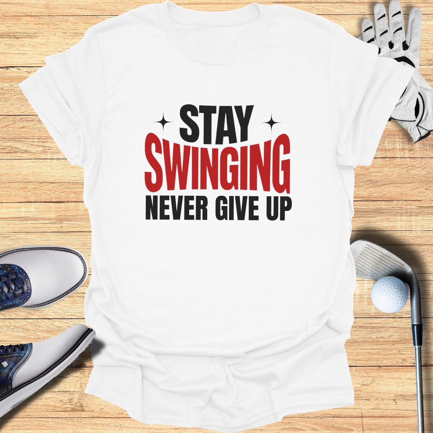 White t-shirt with "Stay Swinging Never Give Up" text, golf club, and shoes.