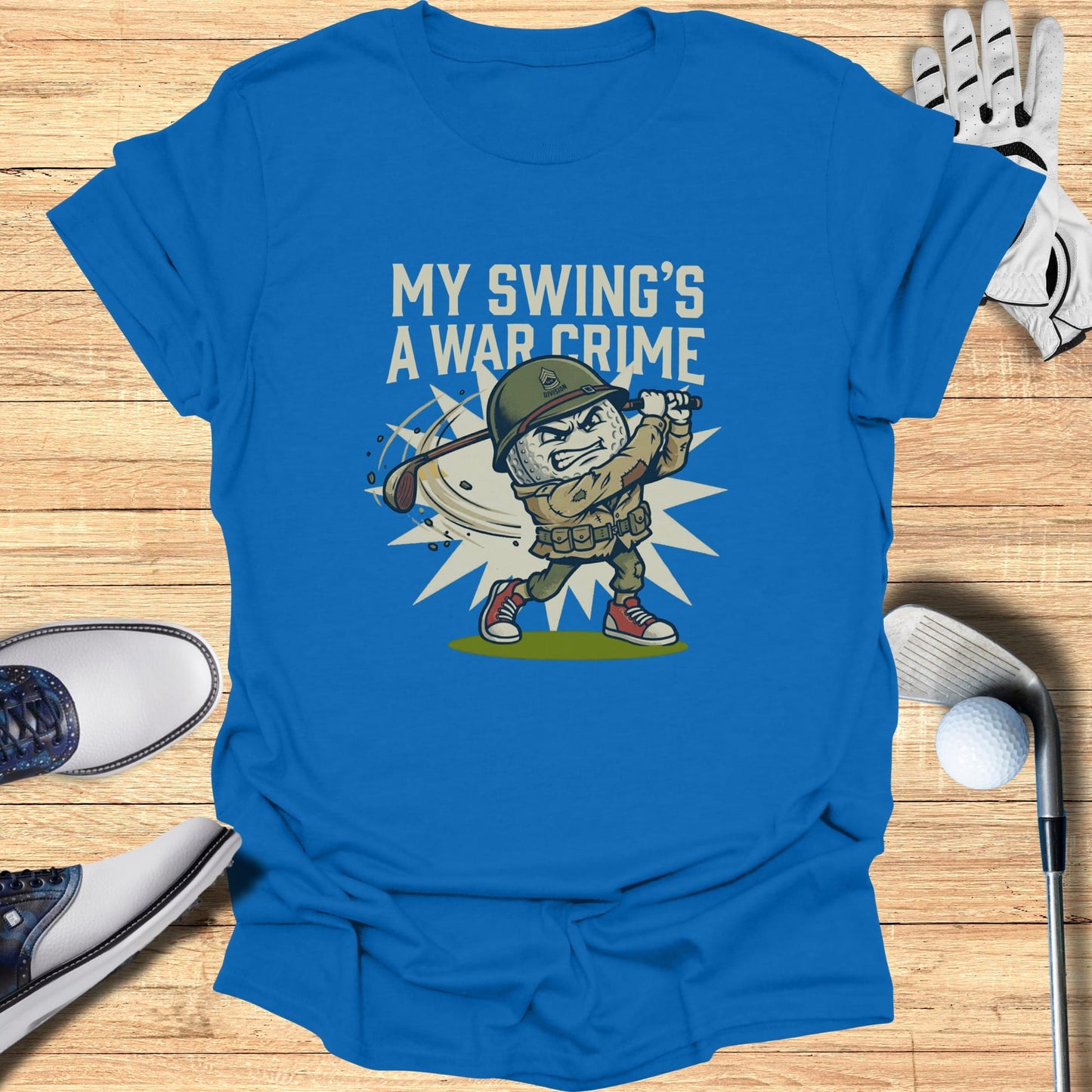 Blue t-shirt with cartoon soldier playing golf and text "MY SWING'S A WAR CRIME".