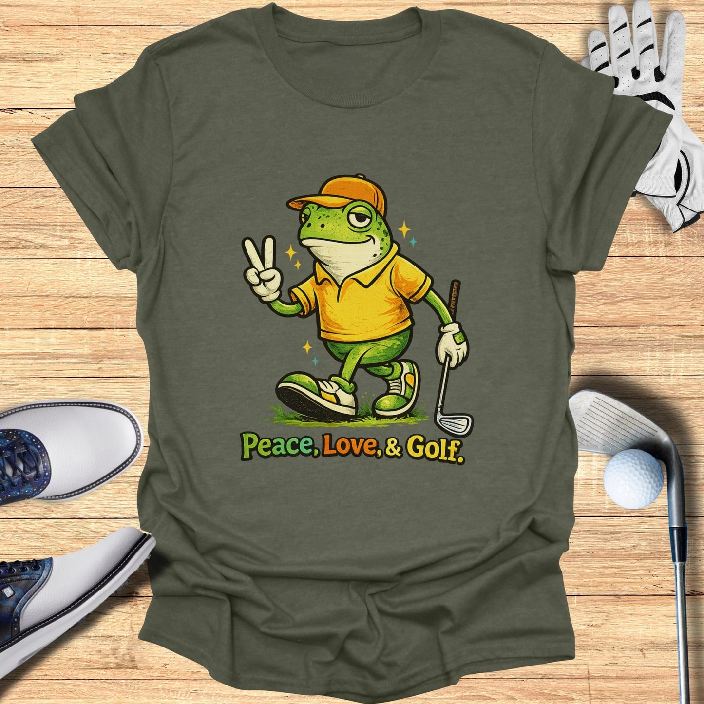 Green t-shirt with cartoon frog giving peace sign, holding golf club.