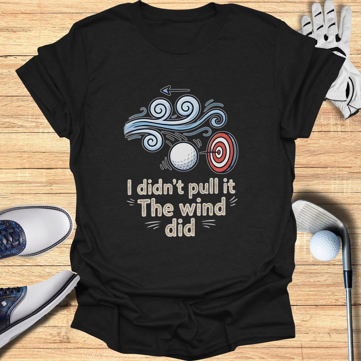 T-shirt with graphic of golf ball, target, and wind with text "I didn't pull it, the wind did".