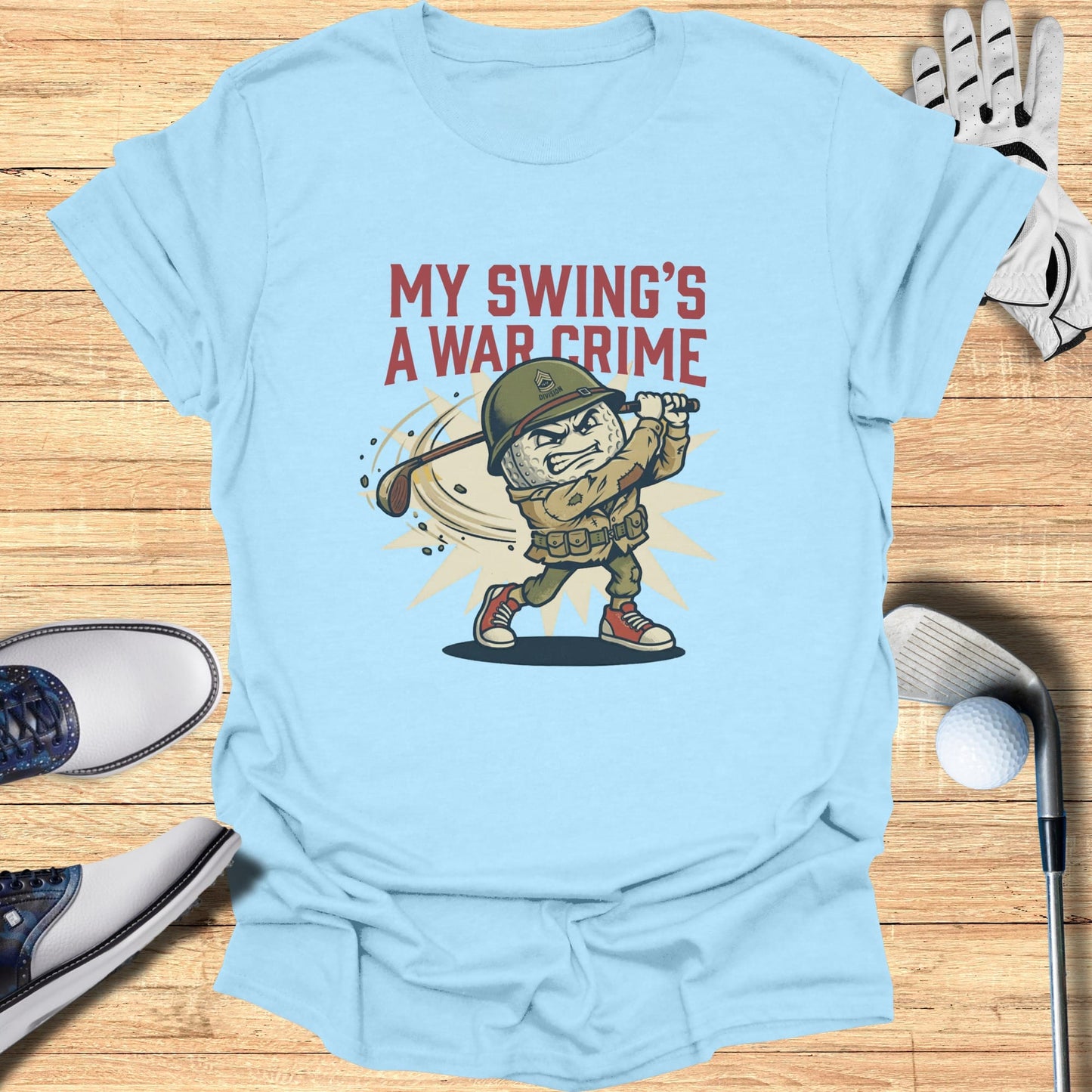 Light blue t-shirt with cartoon soldier golfer and text "MY SWING'S A WAR CRIME".