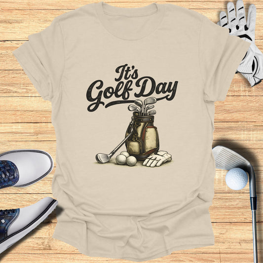Light beige t-shirt with "It's Golf Day" text and golf bag with clubs and balls.