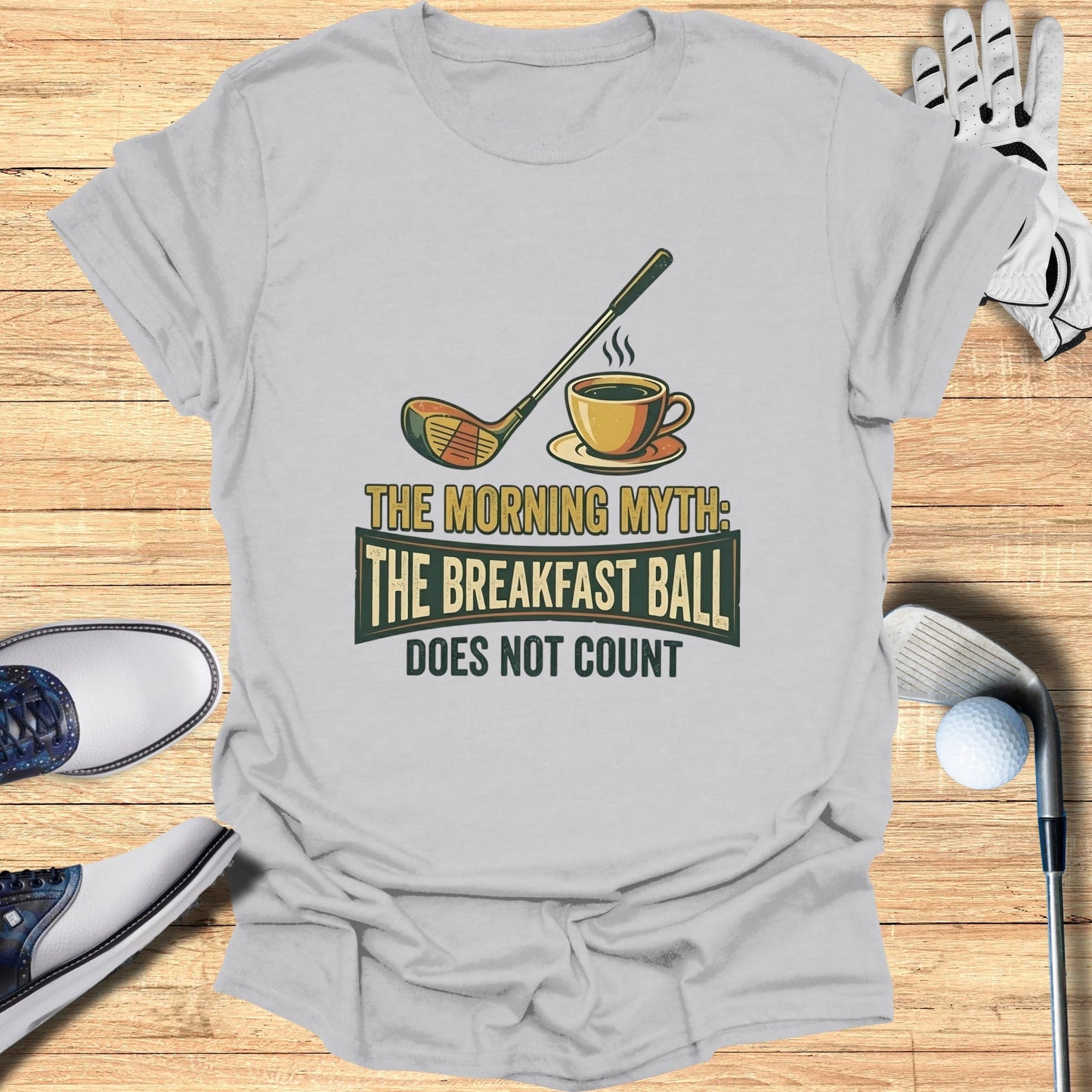 T-shirt with graphic of golf club, coffee cup, and text "The Morning Myth: The Breakfast Ball Does Not Count."