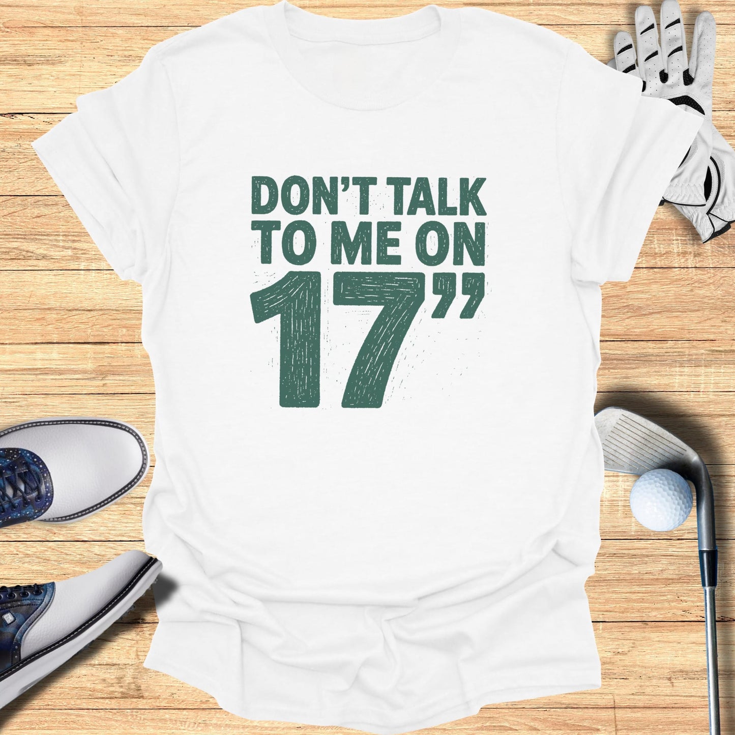 White t-shirt with "Don't talk to me on 17" text and golf accessories.