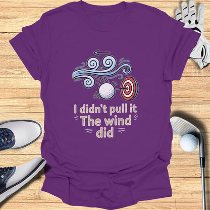 Purple t-shirt with text "I didn't pull it The wind did" and a golf target illustration.