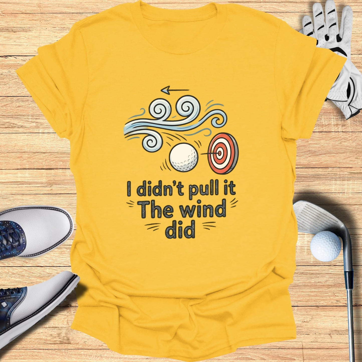 Yellow t-shirt with graphic of target, golf ball, and wind with text "I didn't pull it The wind did".