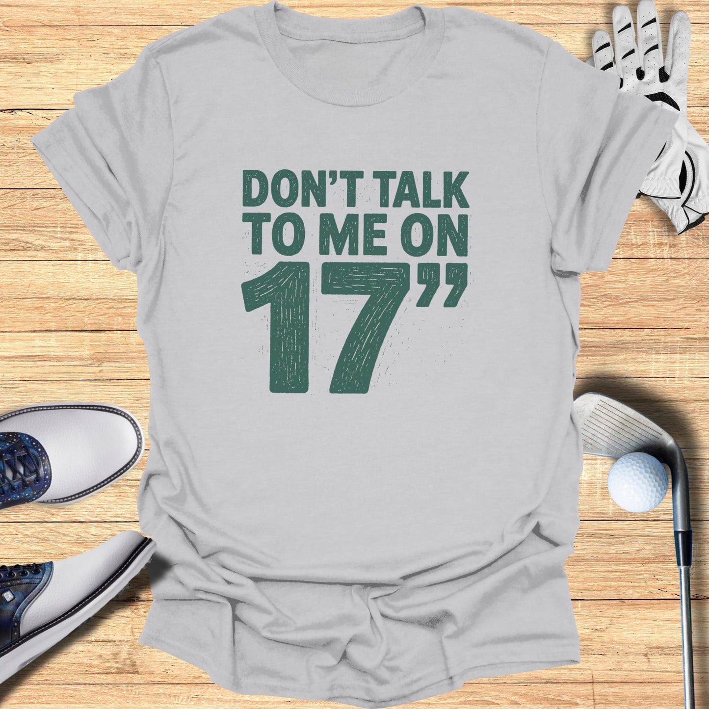 Gray t-shirt with "DON'T TALK TO ME ON 17th" text and golf accessories.