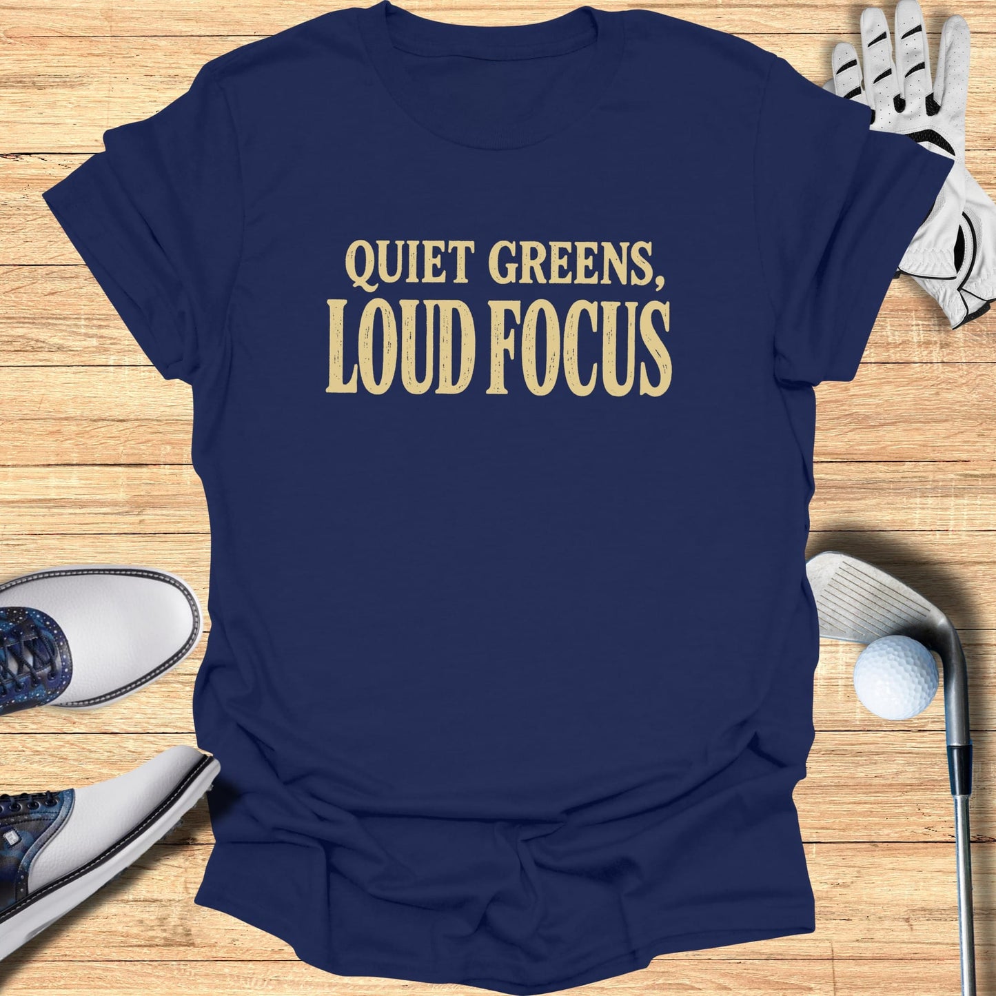 Navy t-shirt with "QUIET GREENS, LOUD FOCUS" in gold text.