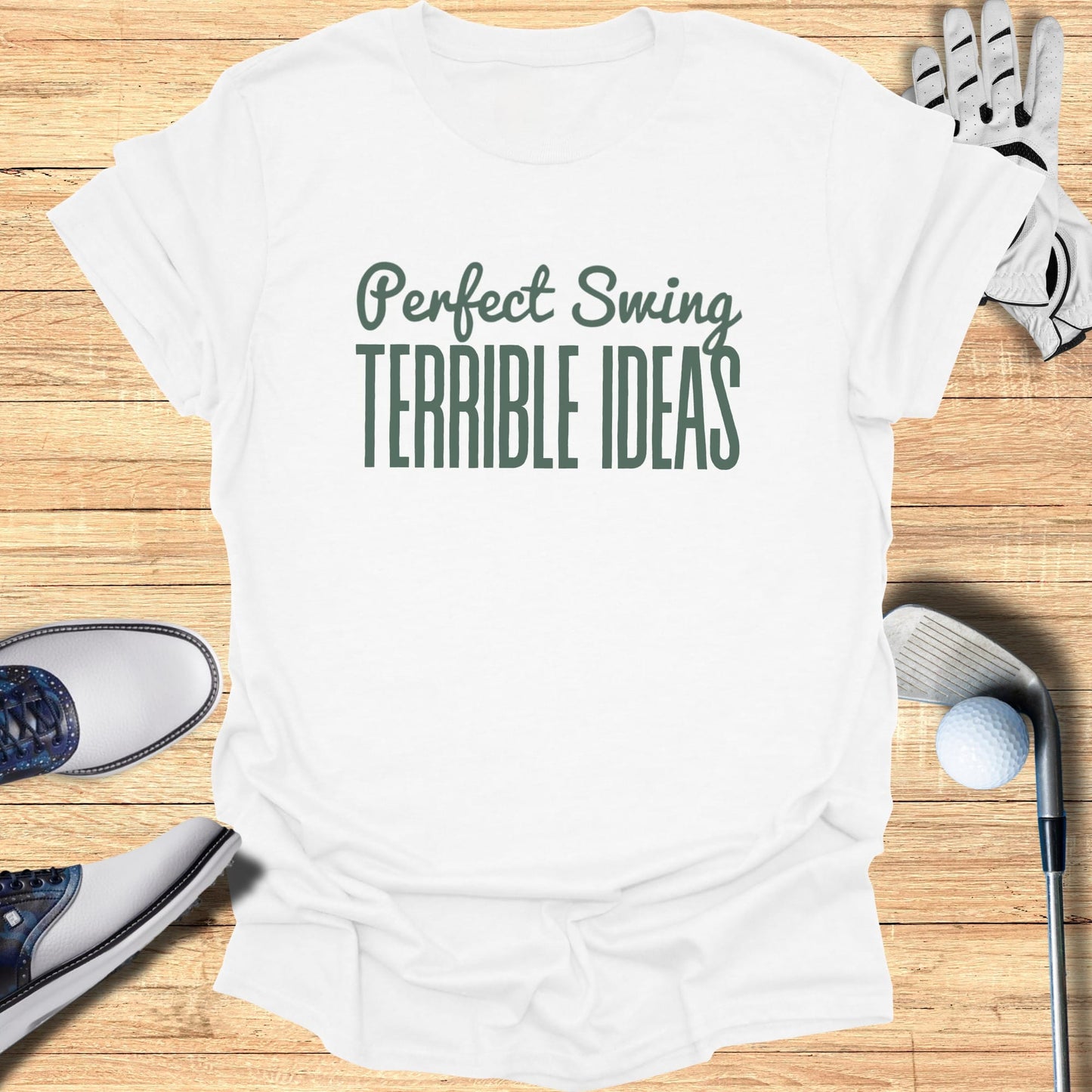 White t-shirt with "Perfect Swing TERRIBLE IDEAS" graphic, golf clubs, shoes, ball.