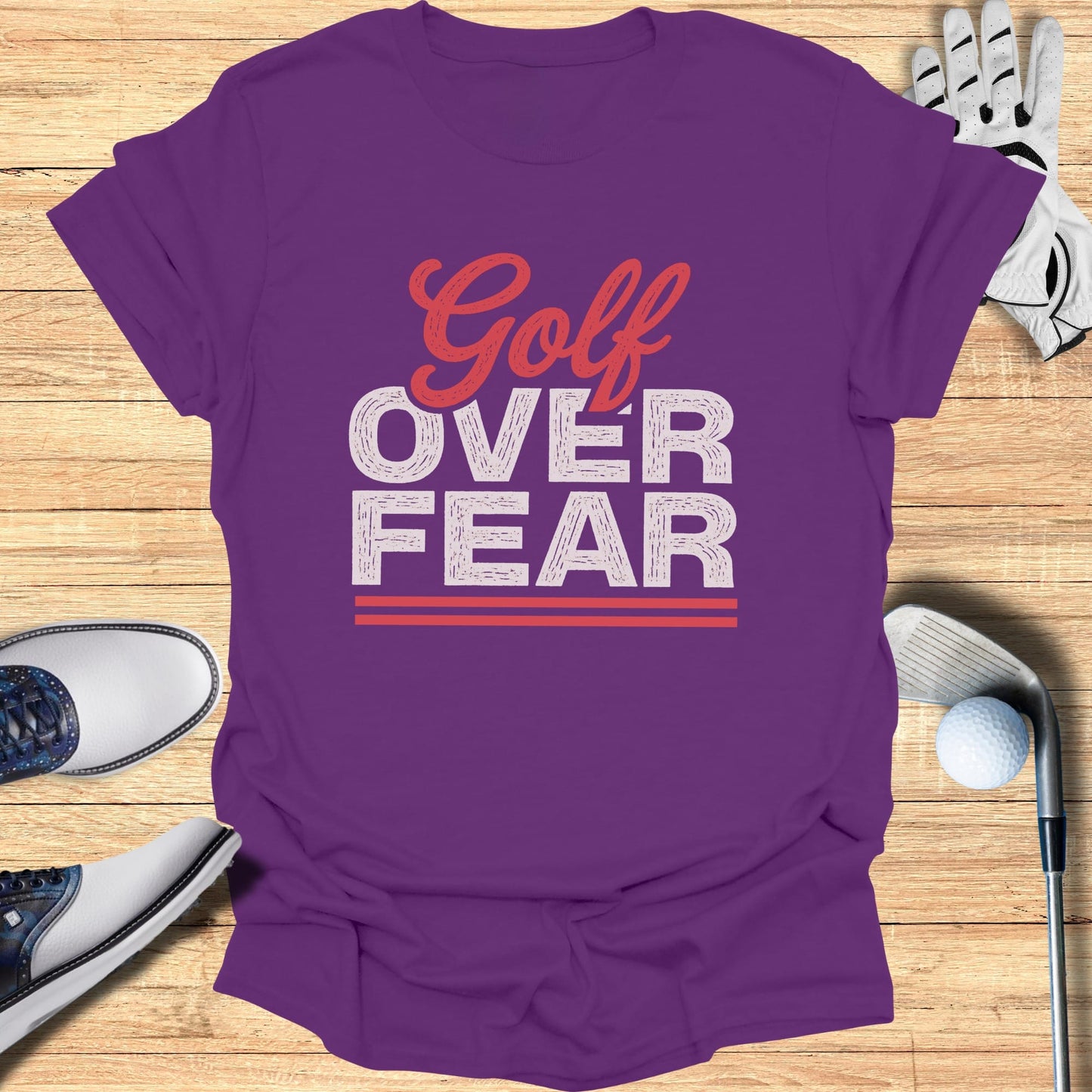 Purple t-shirt with "Golf Over Fear" text, golf shoes, glove, and ball.