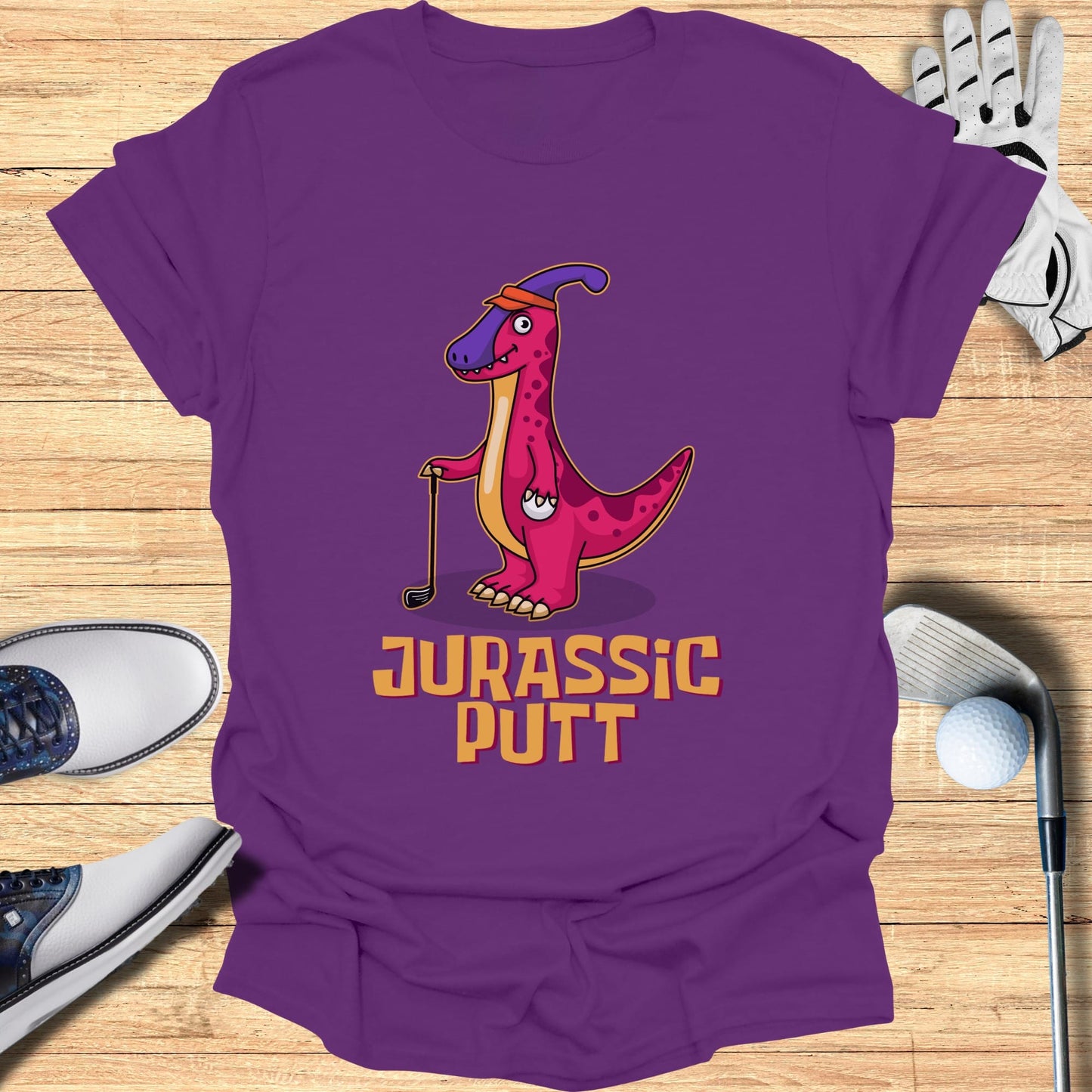 Purple t-shirt with cartoon dinosaur playing golf, text "Jurassic Putt".
