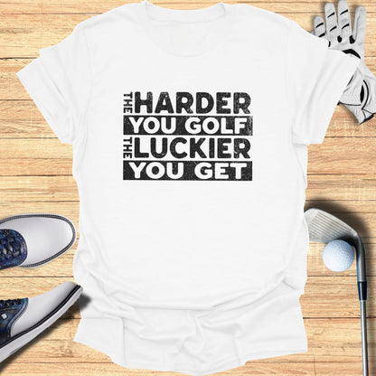 White t-shirt with "The Harder You Golf The Luckier You Get" text.