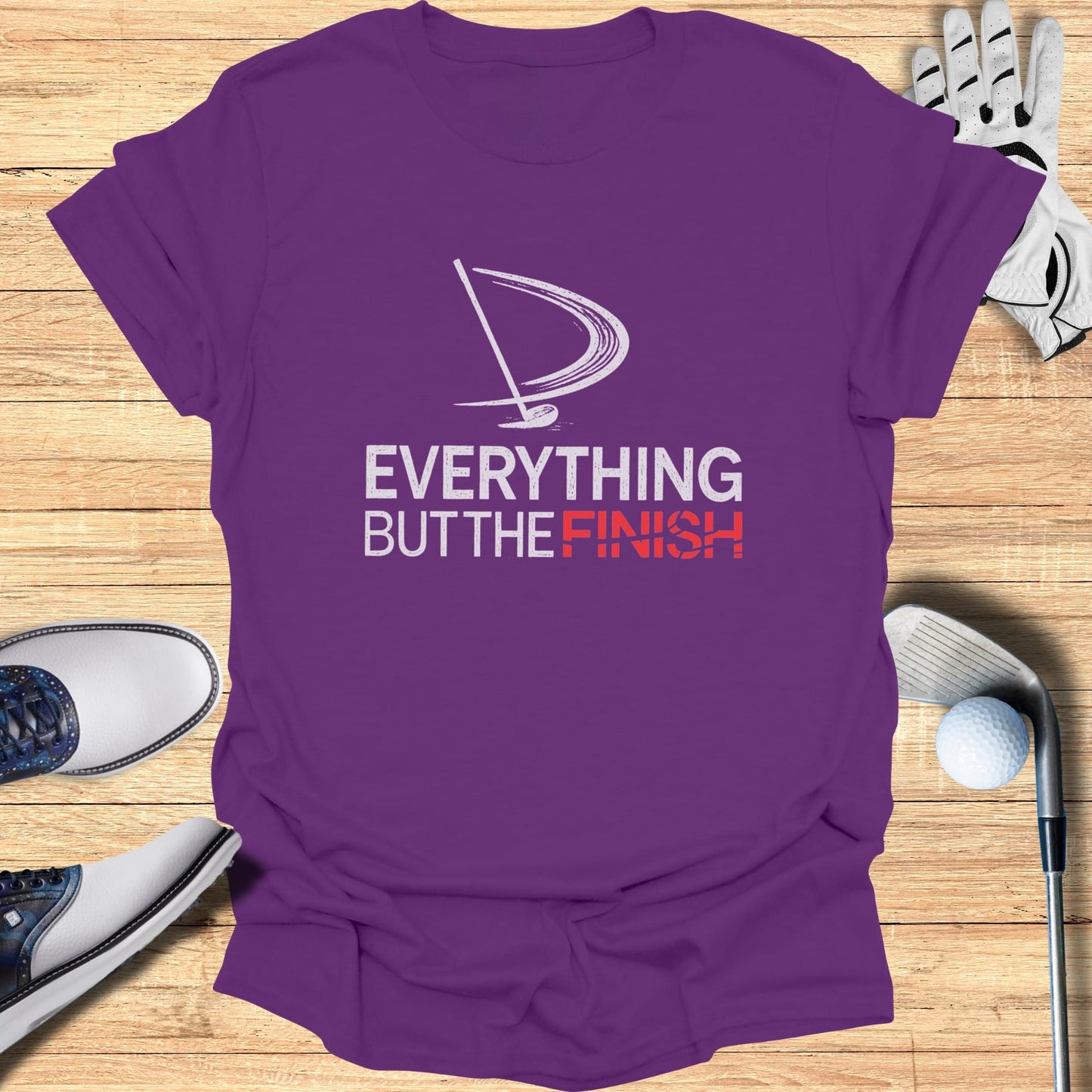 Purple t-shirt with "Everything But The Finish" text and golf accessories.