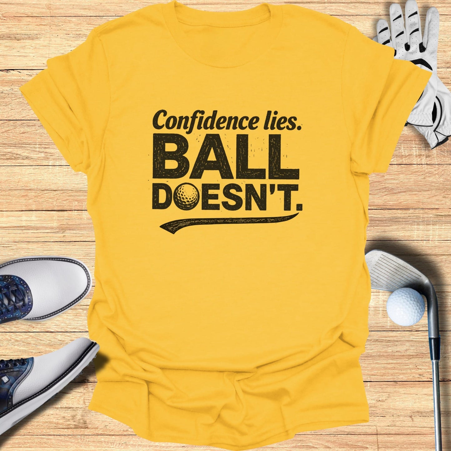 Yellow t-shirt with "Confidence lies. BALL DOESN'T." text and golf accessories.