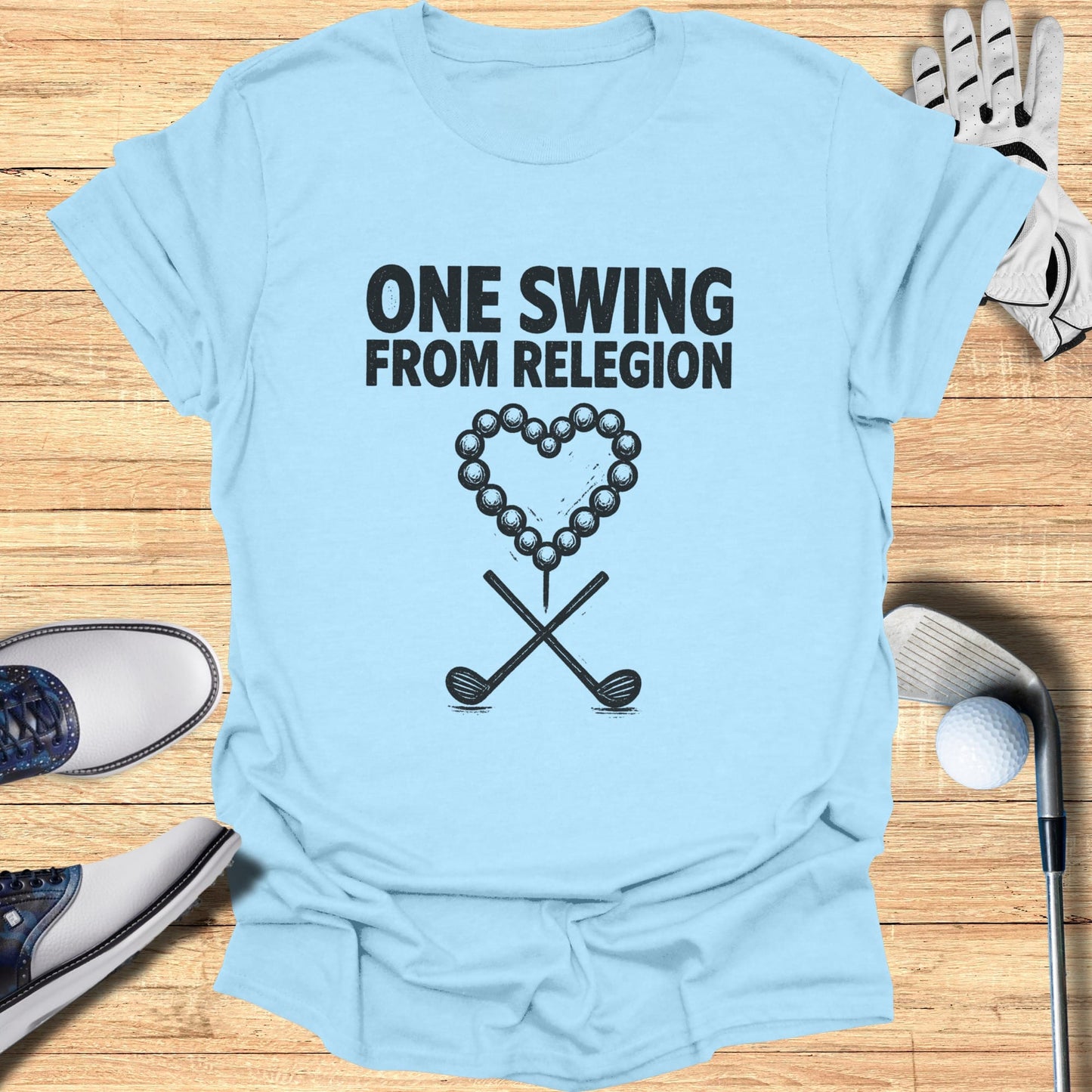 Light blue t-shirt with "ONE SWING FROM RELEGION" and golf ball heart.