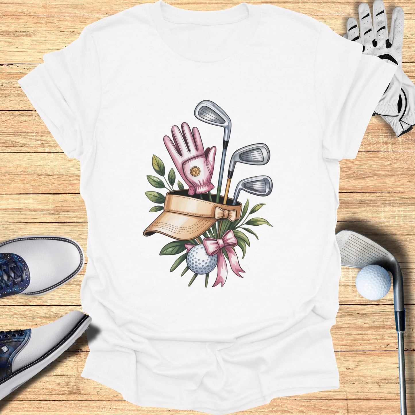 White t-shirt with graphic of golf clubs, ball, glove, and visor with pink bow.