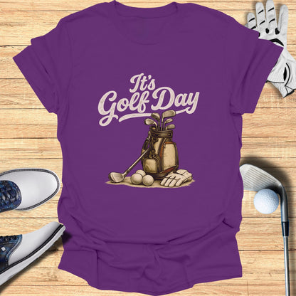 Purple t-shirt with "It's Golf Day" graphic of golf bag, clubs, balls, and glove.