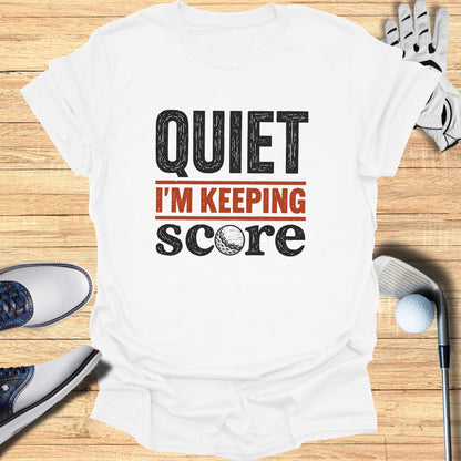 White t-shirt with "QUIET I'M KEEPING SCORE" and golf ball graphic.