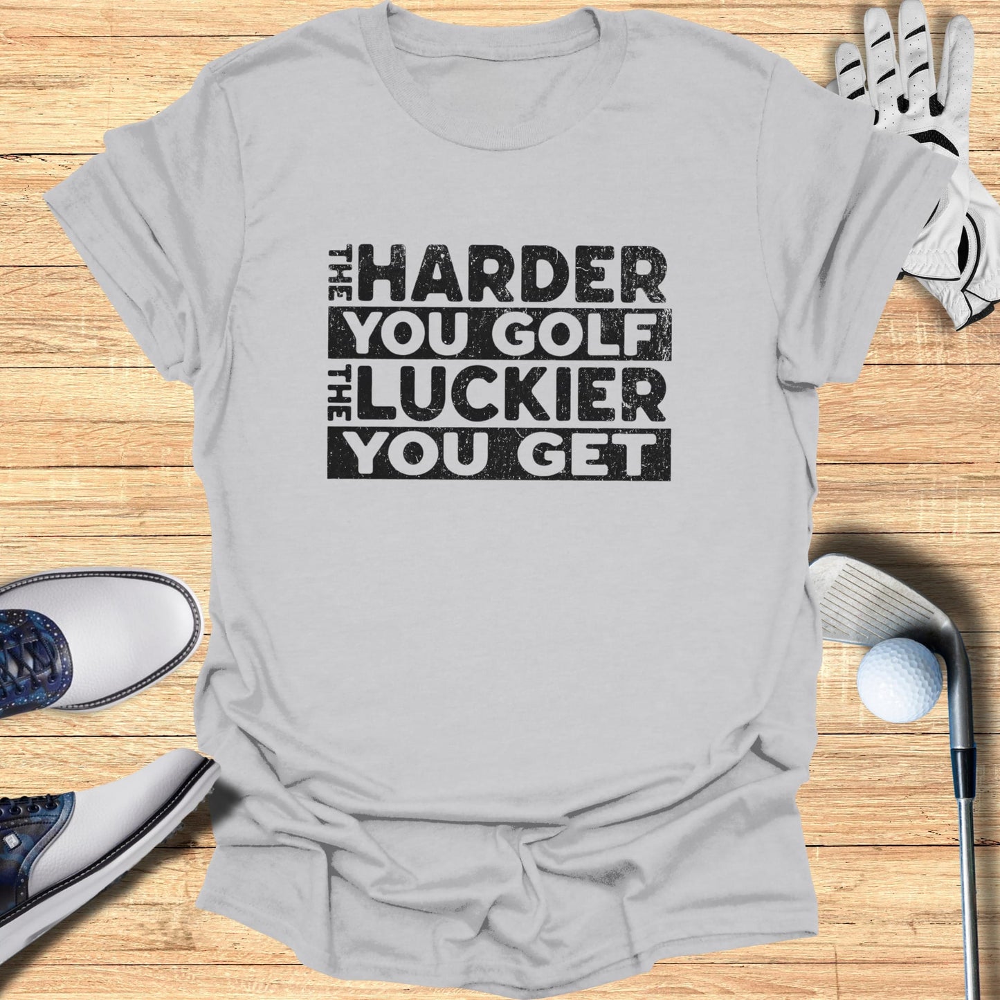 T-shirt with text "The harder you golf the luckier you get".