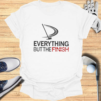 White t-shirt with "EVERYTHING BUT THE FINISH" text and golf accessories.